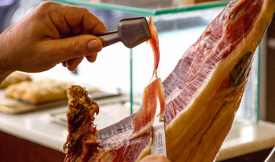 Un cortador profesional de jamu00f3n saca lonchas de una pata de cerdo ibu00e9rico (Foto Junta de Andalucu00eda)