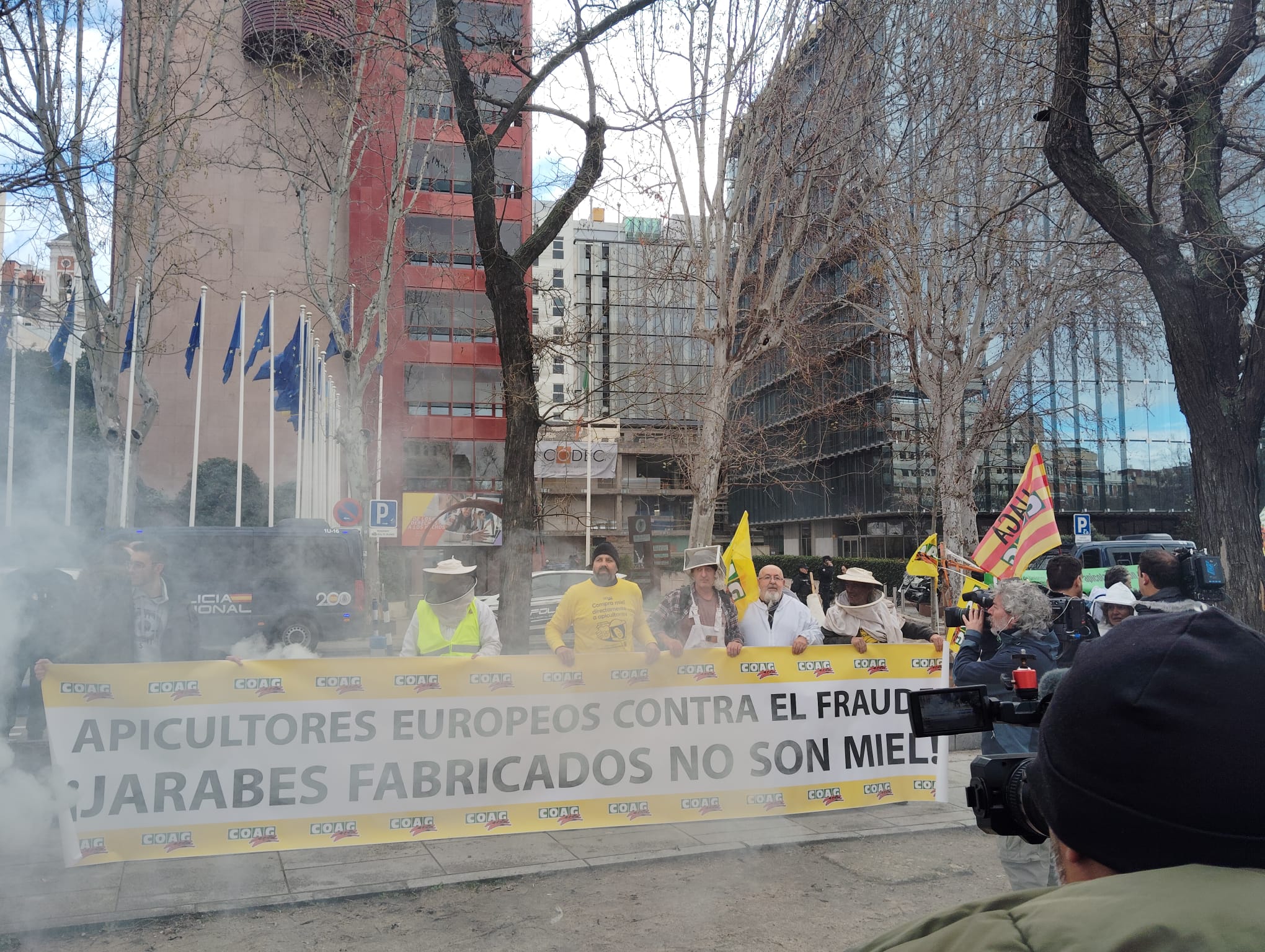 Pancarta 'Los jarabes fabricados no son miel' entre el humo de los ahumadores apícolas (Foto COAG)